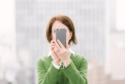 woman with a smart phone in a business sector live streaming with Facebook Live