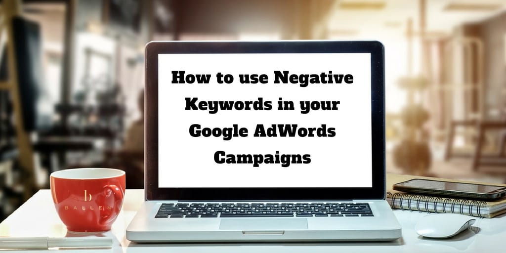 Computer screen on a table reads how to use negative keywords in your google Adwords Campaign, Coffee cup nearby