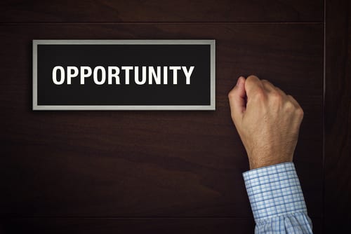 Person is knocking on a door and the door has the word opportunity