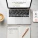Laptop with a blog post and phone showing a product page on a marble desk — affiliate marketing examples